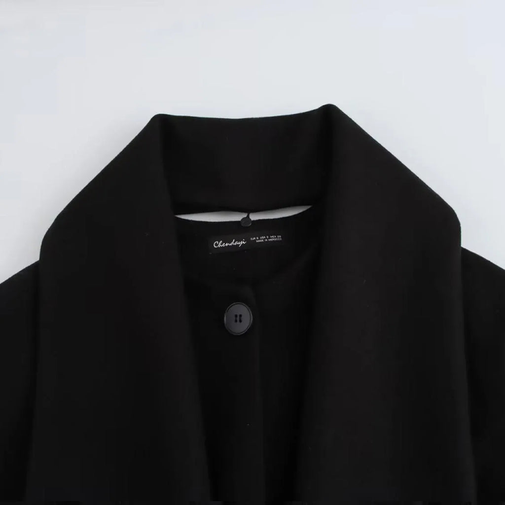 Women's long black overcoat with an artificial fur collar, shown with side pockets.