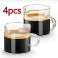 Two white modern double mouth transparent glass coffee cups on a table.