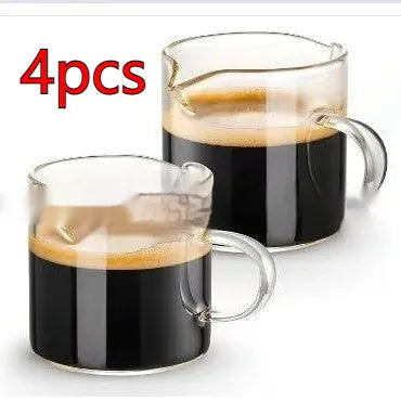 Two white modern double mouth transparent glass coffee cups on a table.
