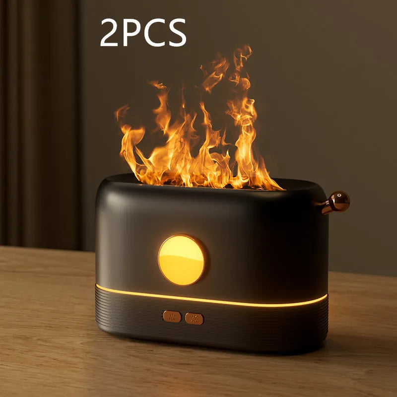 Black USB humidifier with flickering flame effect on a wooden desk next to a plant.