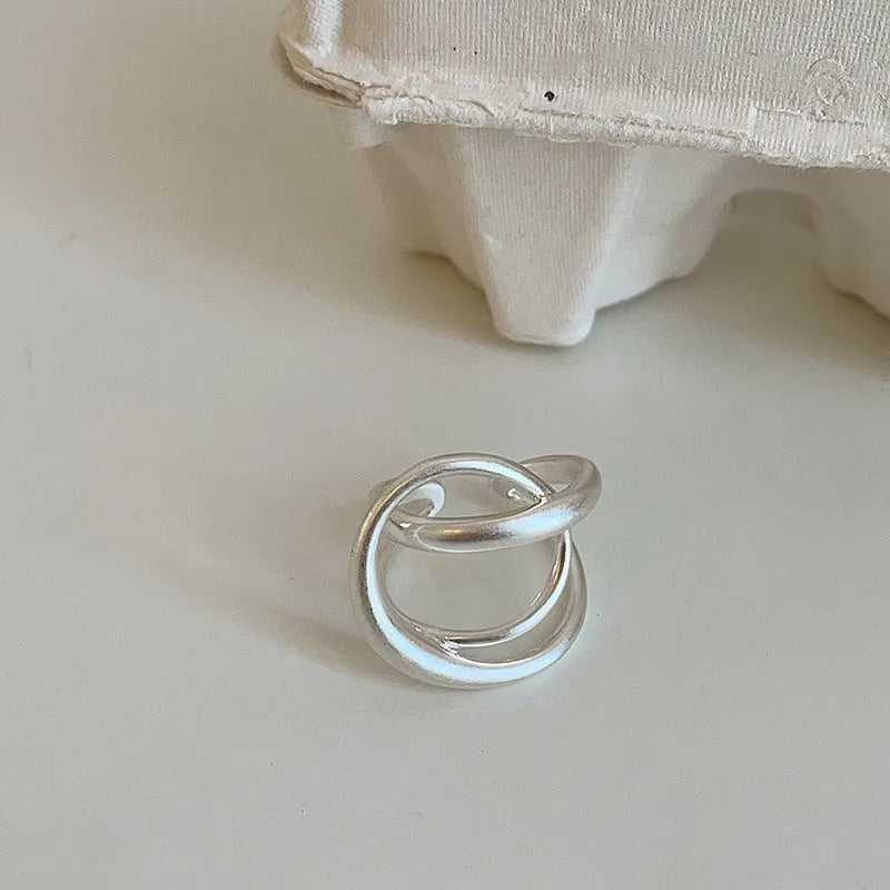Geometric open ring for women with a three-dimensional interlaced design in matte metal.