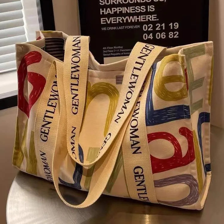 Large canvas tote bag with printed design showing black letters, available in multiple pattern options