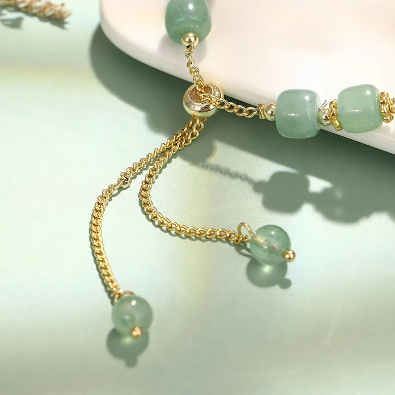 Rabbit charm bracelet with green aventurine or strawberry quartz stones and gold accents on a wrist.