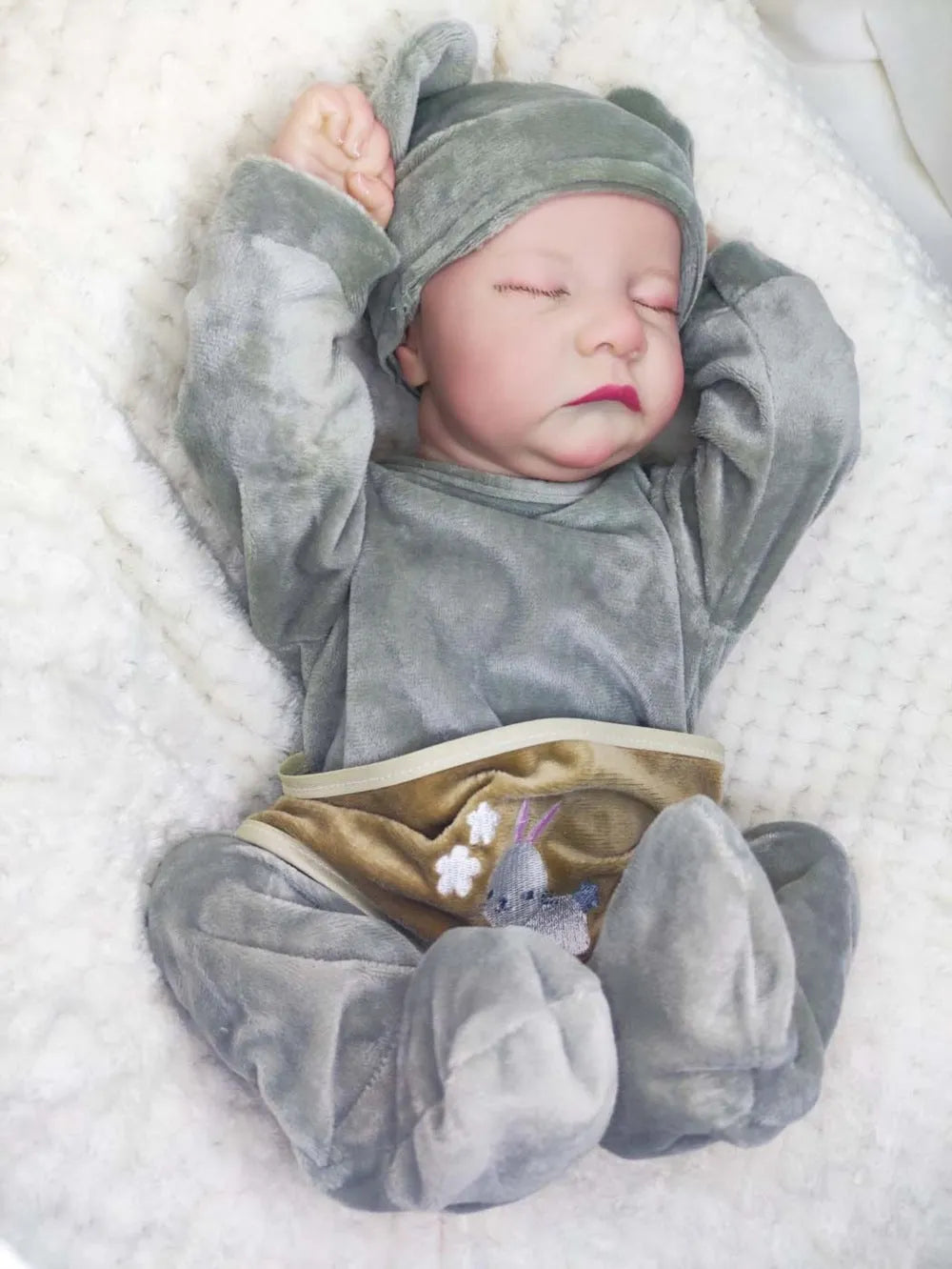 18-inch reborn doll with cloth body in soft pink romper sitting on table
