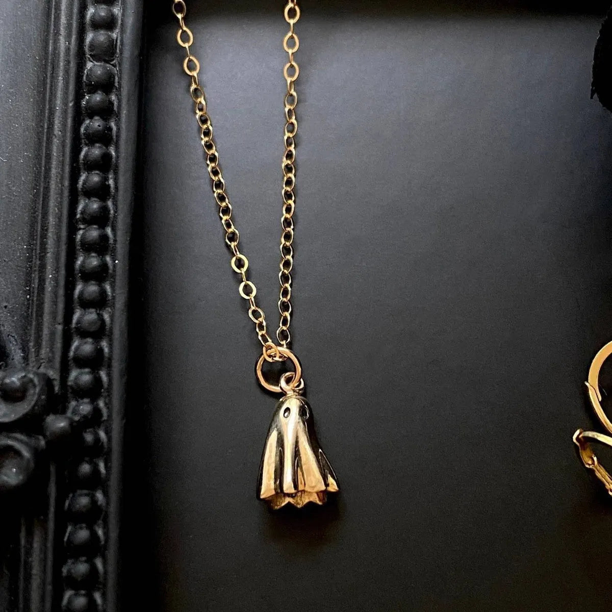 A ghost-themed pendant necklace on a twisted stainless steel chain, showing the titanium steel pendant detail.
