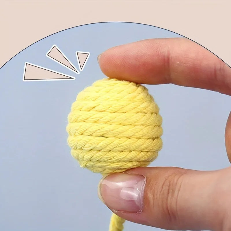 Green cat toy ball with attached rope on a wooden floor, shown next to a yellow 3cm size version.