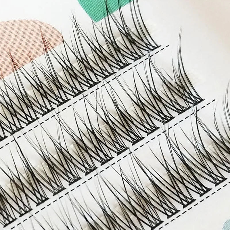 Black V-shaped fairy fishtail false eyelashes with thick segments on a clear tray.