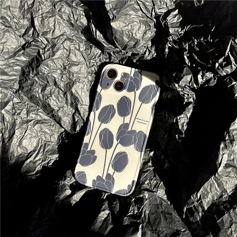 Black silicone iPhone case with a detailed white tulip pattern on the back.