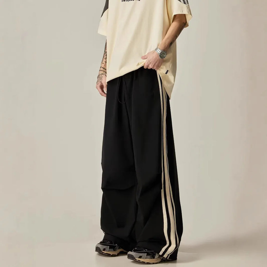 Man wearing black high-waist wide-leg climbing trousers in a casual setting