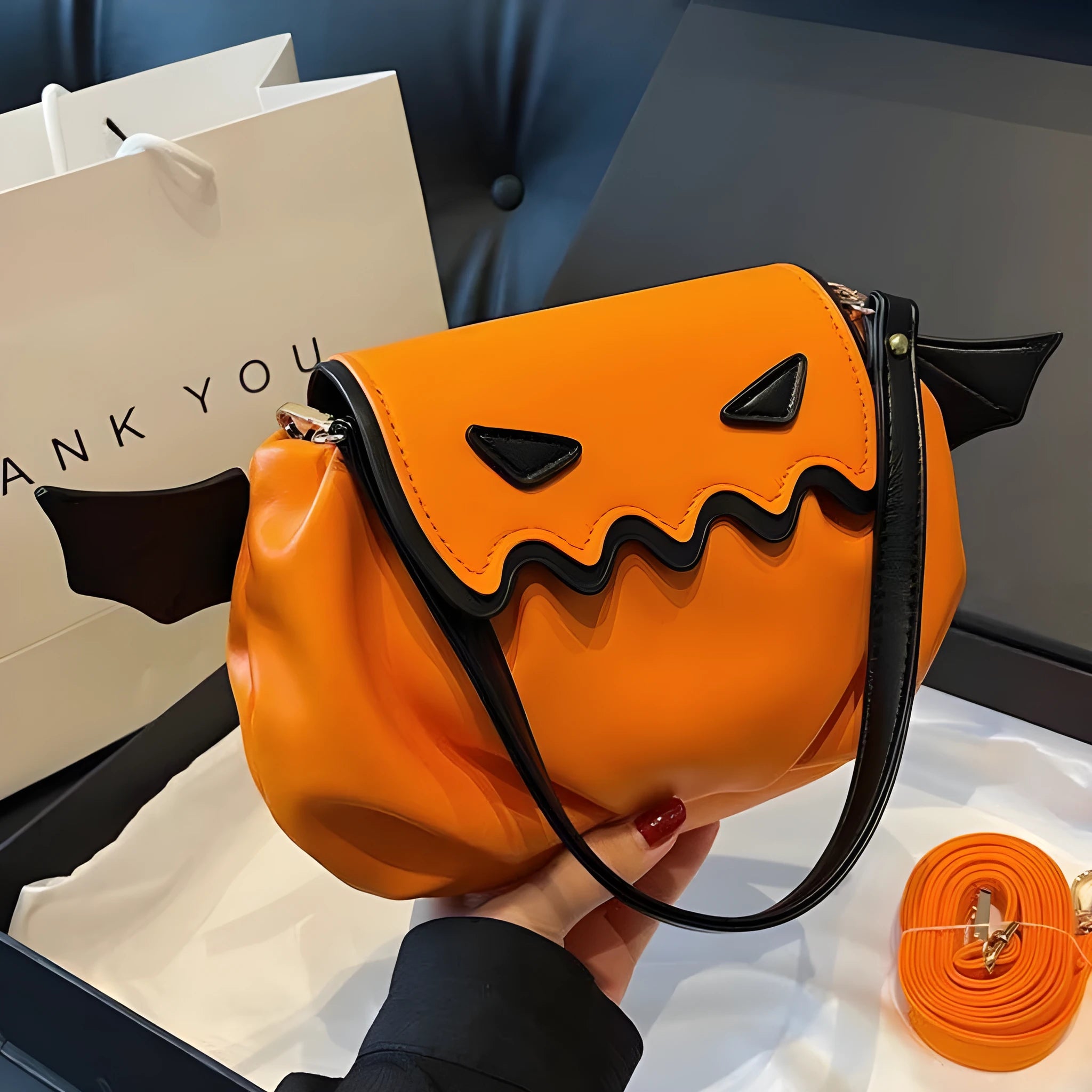 Orange PU crossbody bag with pumpkin cartoon shape and small wings, placed on a neutral background