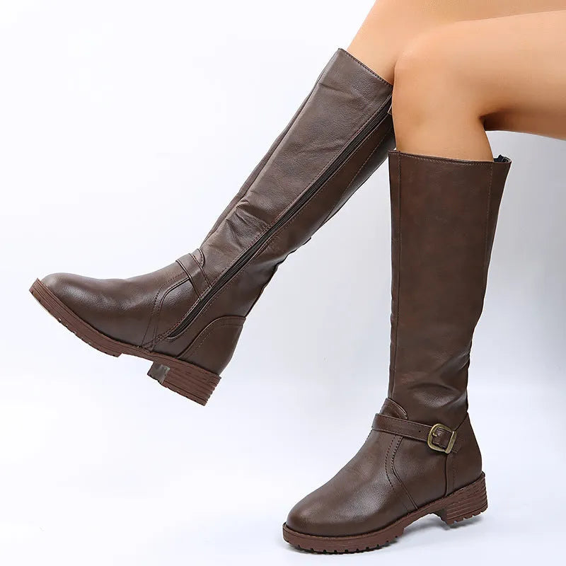 Women's black knight boots with belt buckle details and square heel on model