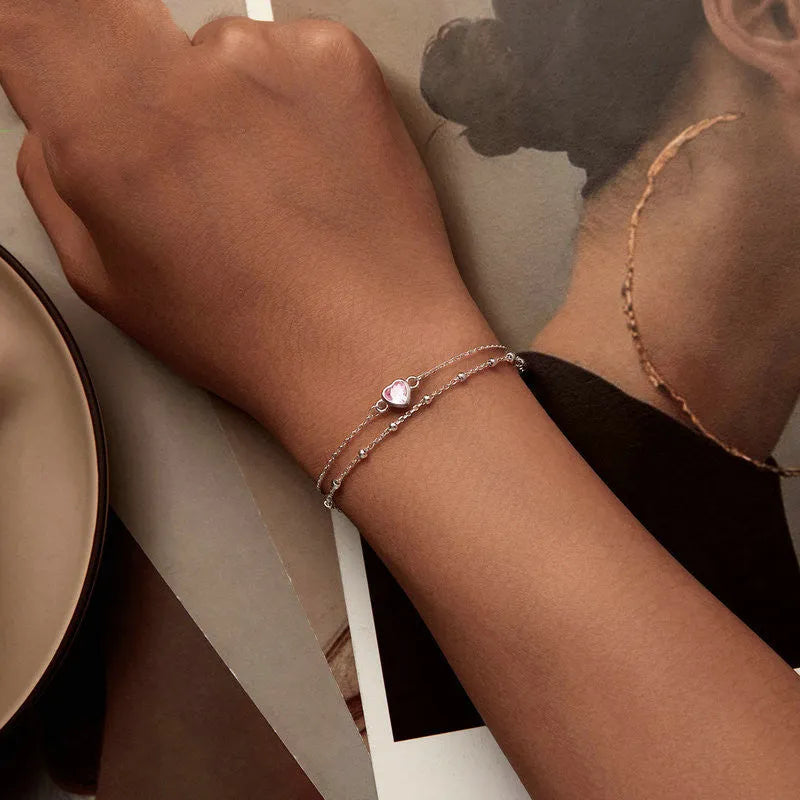 Women's sterling silver bracelet with a small heart-shaped charm on an adjustable chain.