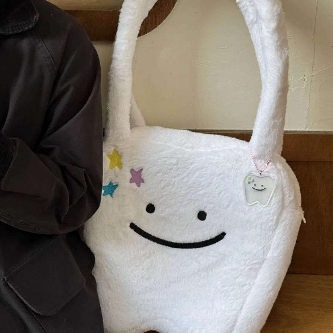 White plush tote bag with large cute teeth graphic, showing crossbody strap and zip opening.