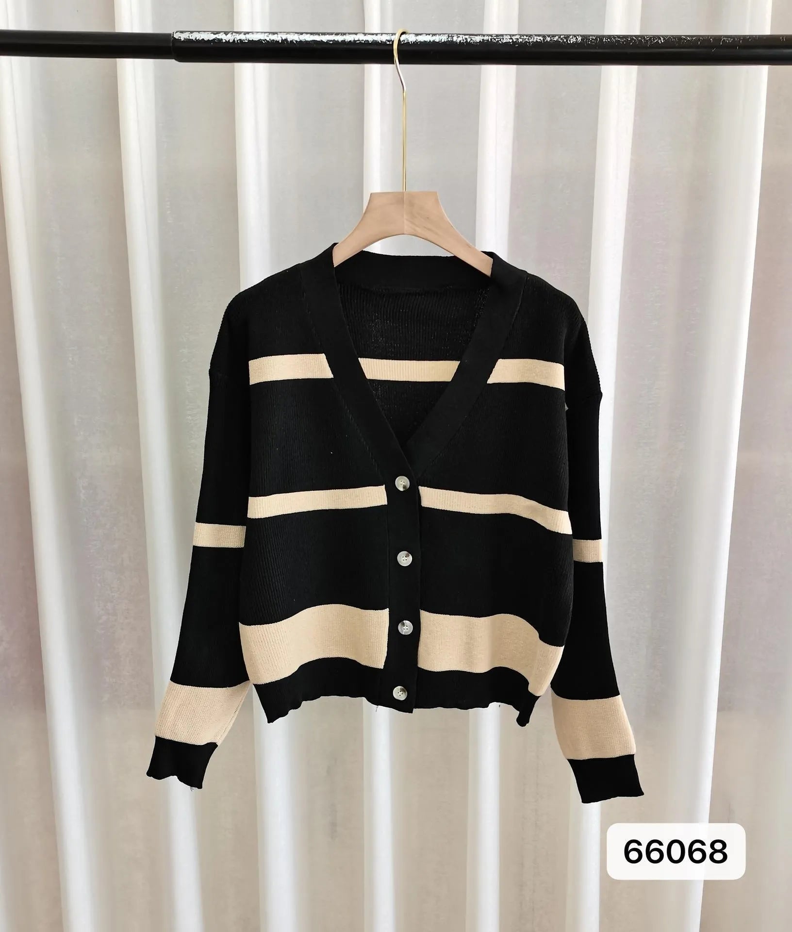 A woman wearing a slim-fit black and white striped V-neck knitted cardigan.