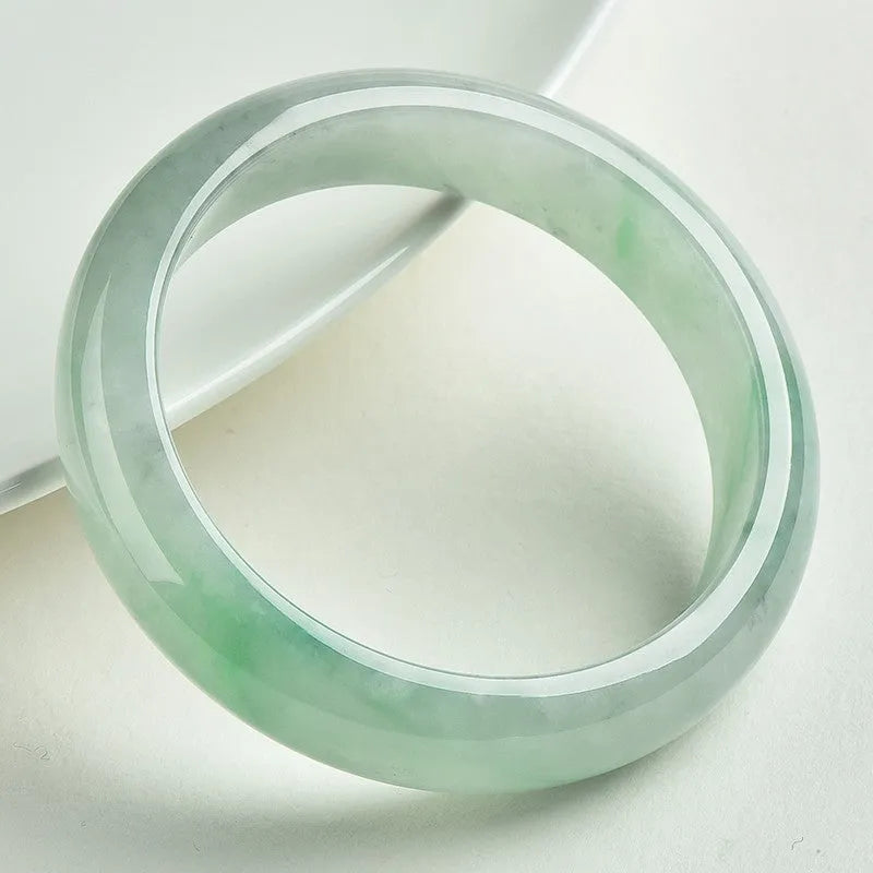 Light green jade bracelet on a white background, showing natural stone texture.