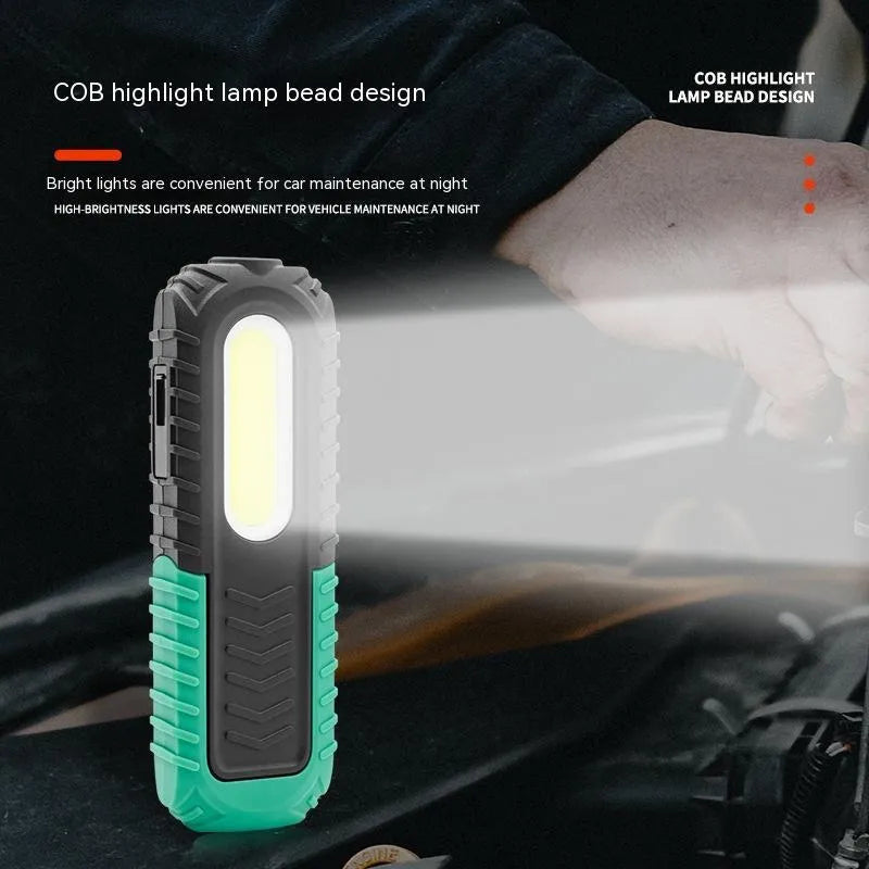 Black and green USB rechargeable automotive inspection work light on a workshop bench.
