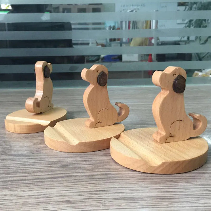 Solid wood cartoon puppy phone bracket with brown spray paint on a desk holding a smartphone upright.