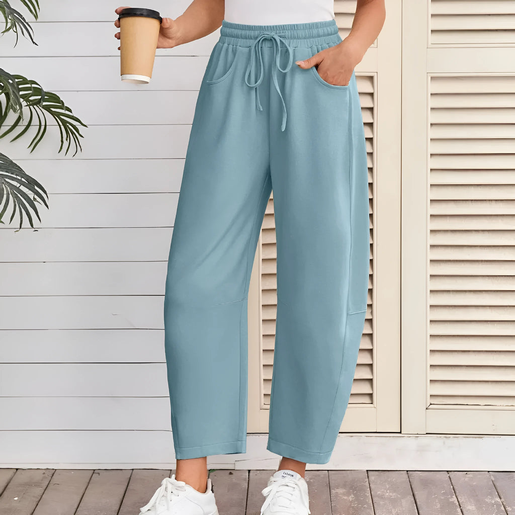 Woman wearing loose grey cropped sweatpants with drawstring waist and side pockets, street fashion style.