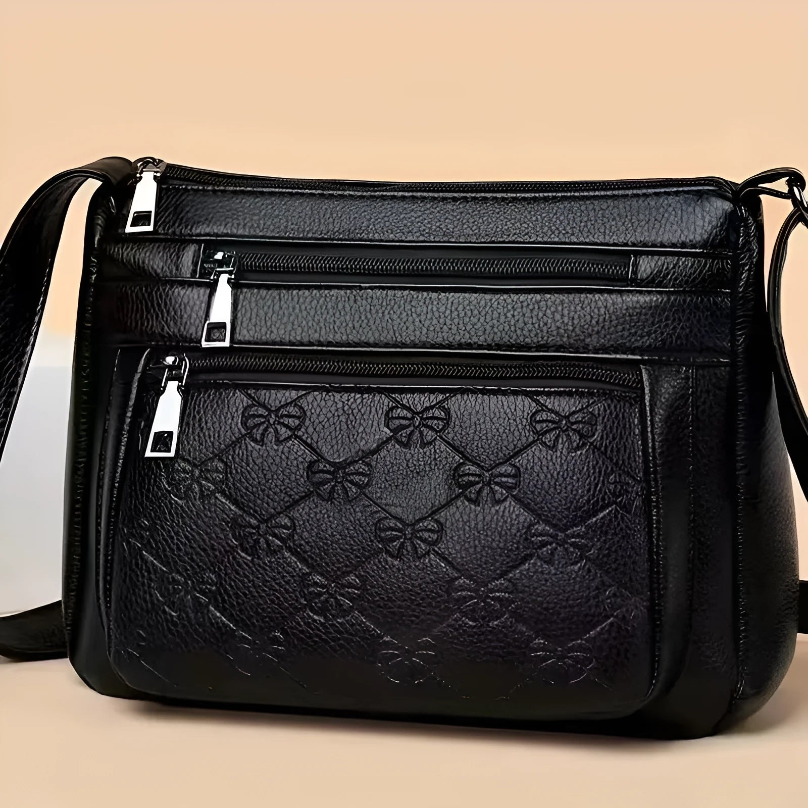 Black women's crossbody bag with butterfly embossed pattern and adjustable shoulder strap.