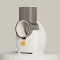 White electric vegetable slicer with rotary grater and suction base on kitchen counter