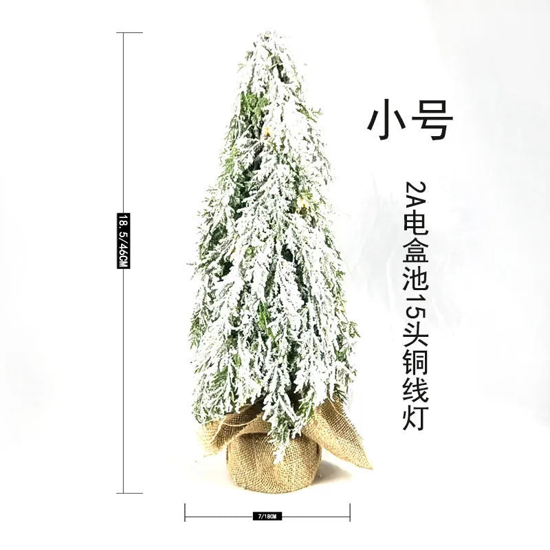 Small 24 inch artificial Christmas tree with lights and snow effect on a desktop