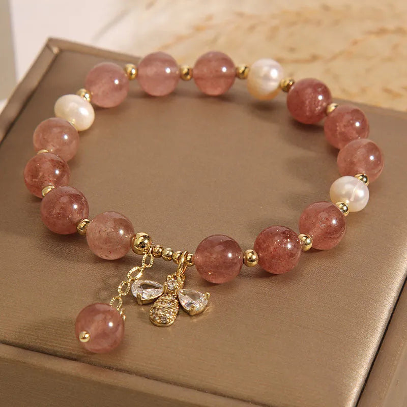 Women's bracelet with three freshwater pearls, a pink strawberry quartz charm, and sparkling zircon stones on an alloy chain.