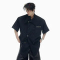Men's loose-fitting short-sleeved casual summer shirt in black, showing splicing detail and lapel collar.