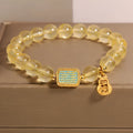 Women's bracelet with yellow citrine stones and sparkling rhinestone details on a white background.