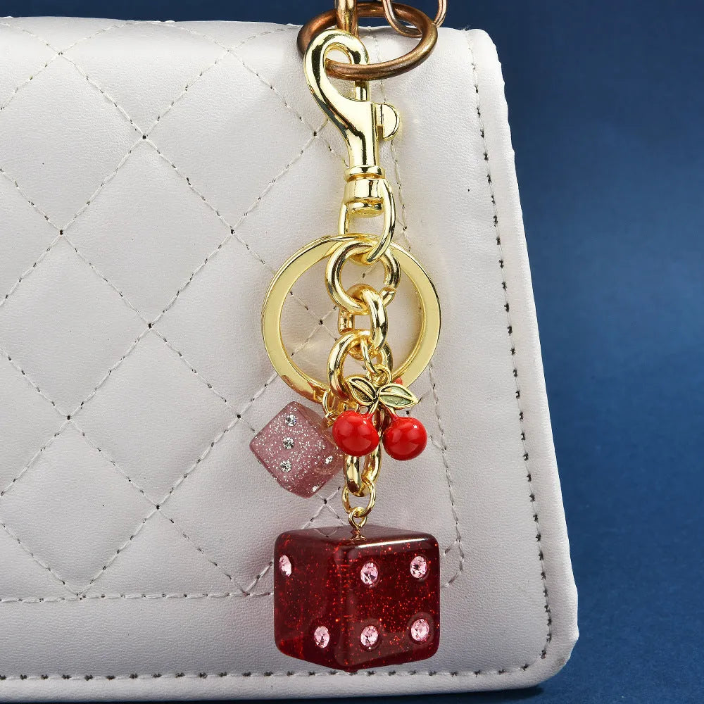 Close-up of a square metal keychain pendant with a two-tone red cherry dice pattern.
