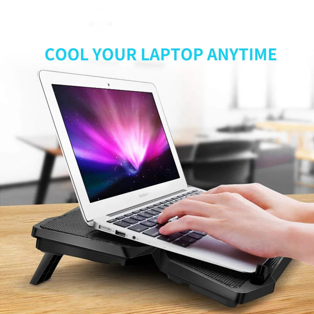 Blue laptop cooling pad with four illuminated fans, two USB ports, and speed control switches on a desk.