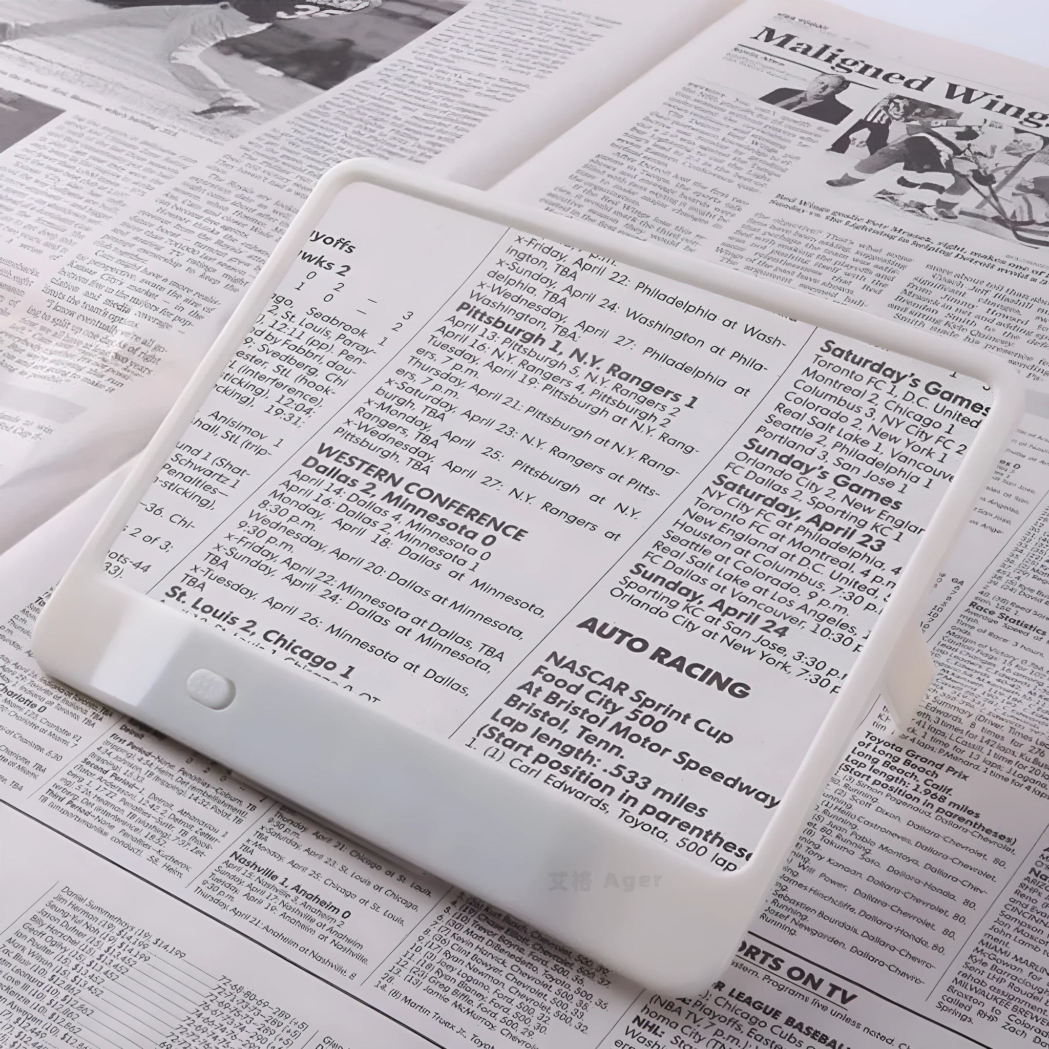 Black and white LED magnifying glass with 3x lens on a desktop next to a book.