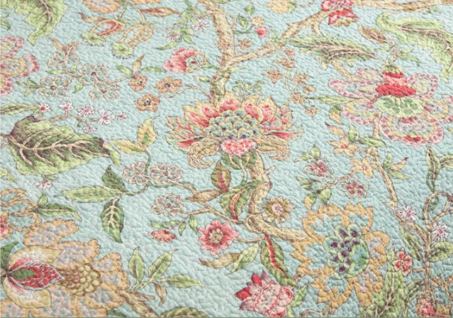 Blue American floral and bird pattern cotton bedspread quilted set of three pieces on a bed.
