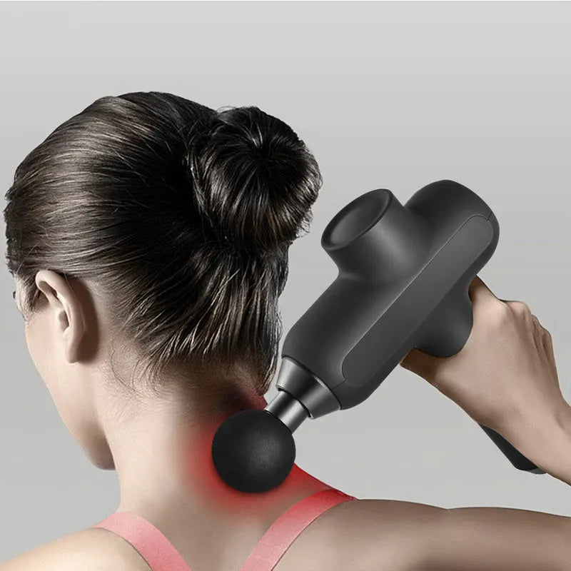 Black electric percussion muscle massager with six different coloured attachment heads on a table.