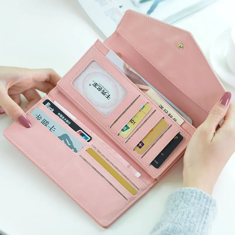 Women's large black three-fold PU leather wallet with buckle closure showing card slots.