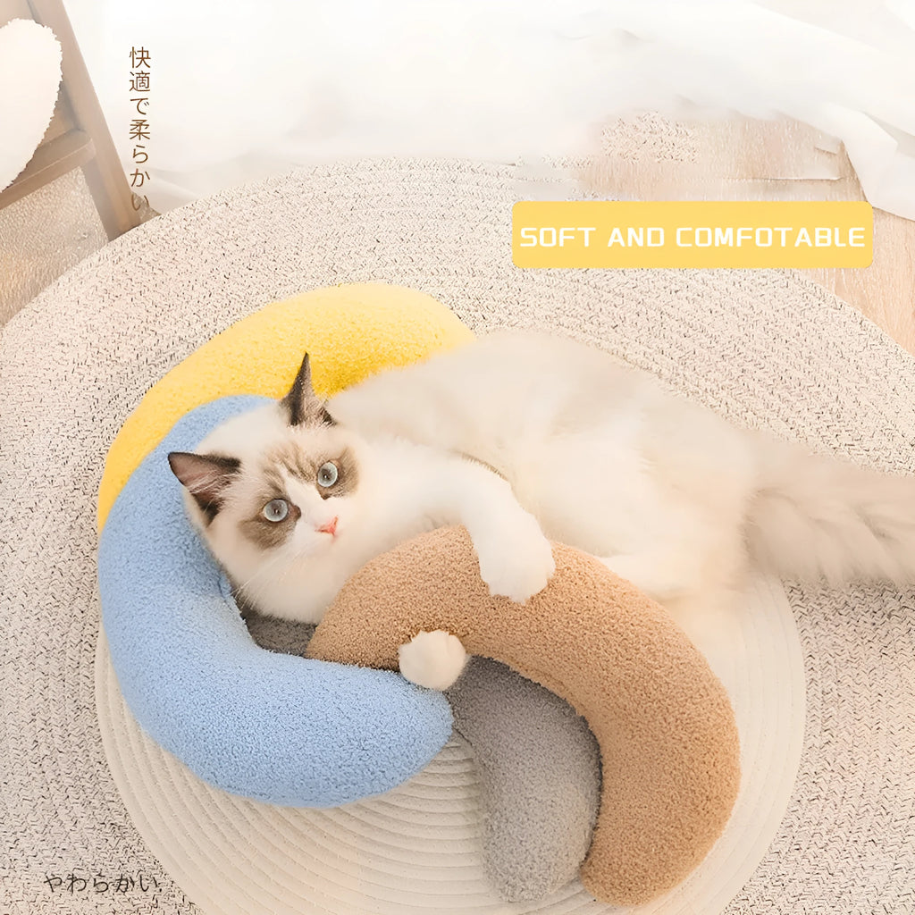 Blue U-shaped cat pillow with an adjustable fabric collar for neck support on a grey sofa