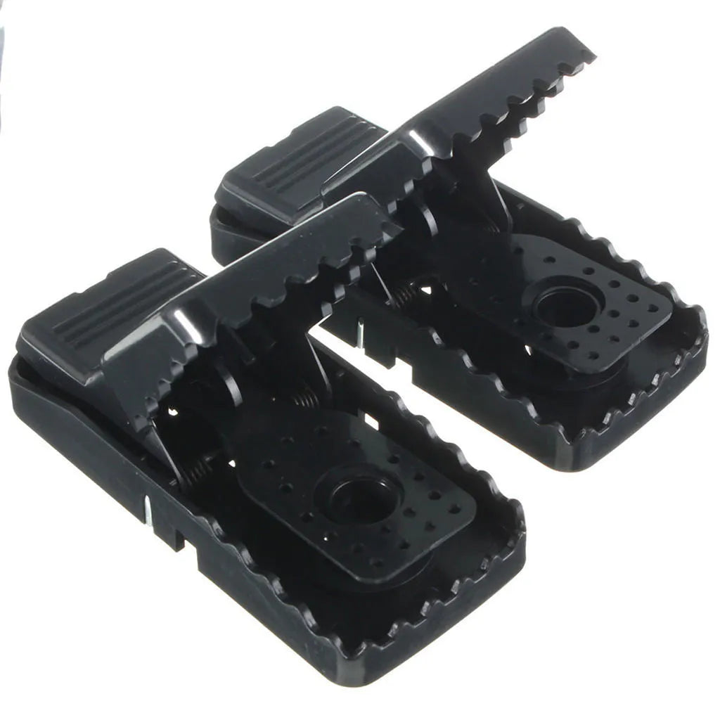 Set of six black plastic snapping mousetraps with smooth surfaces, shown next to a ruler for scale.