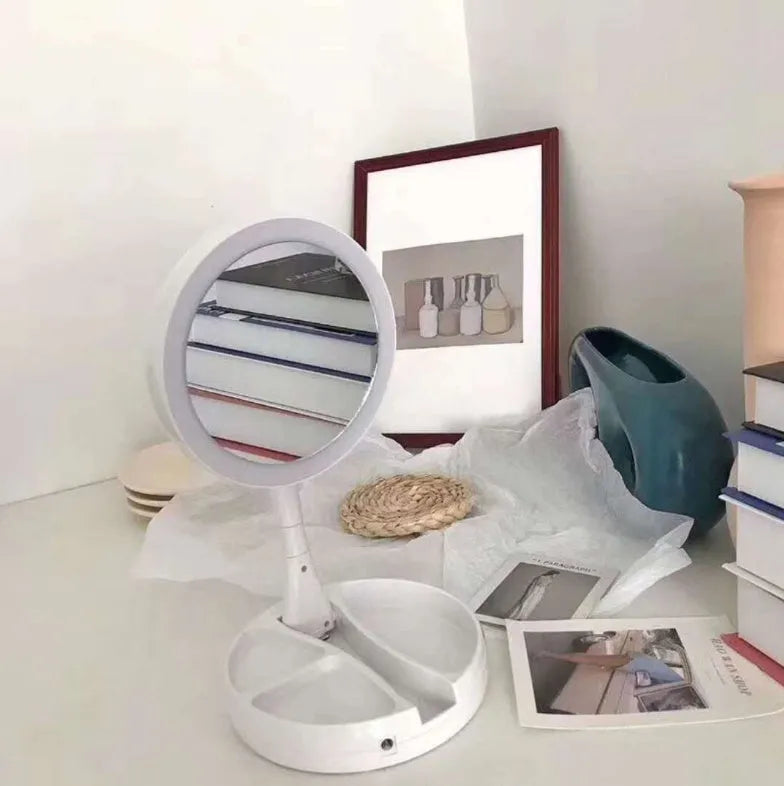 White foldable LED vanity mirror with a ring light, shown open on a table.