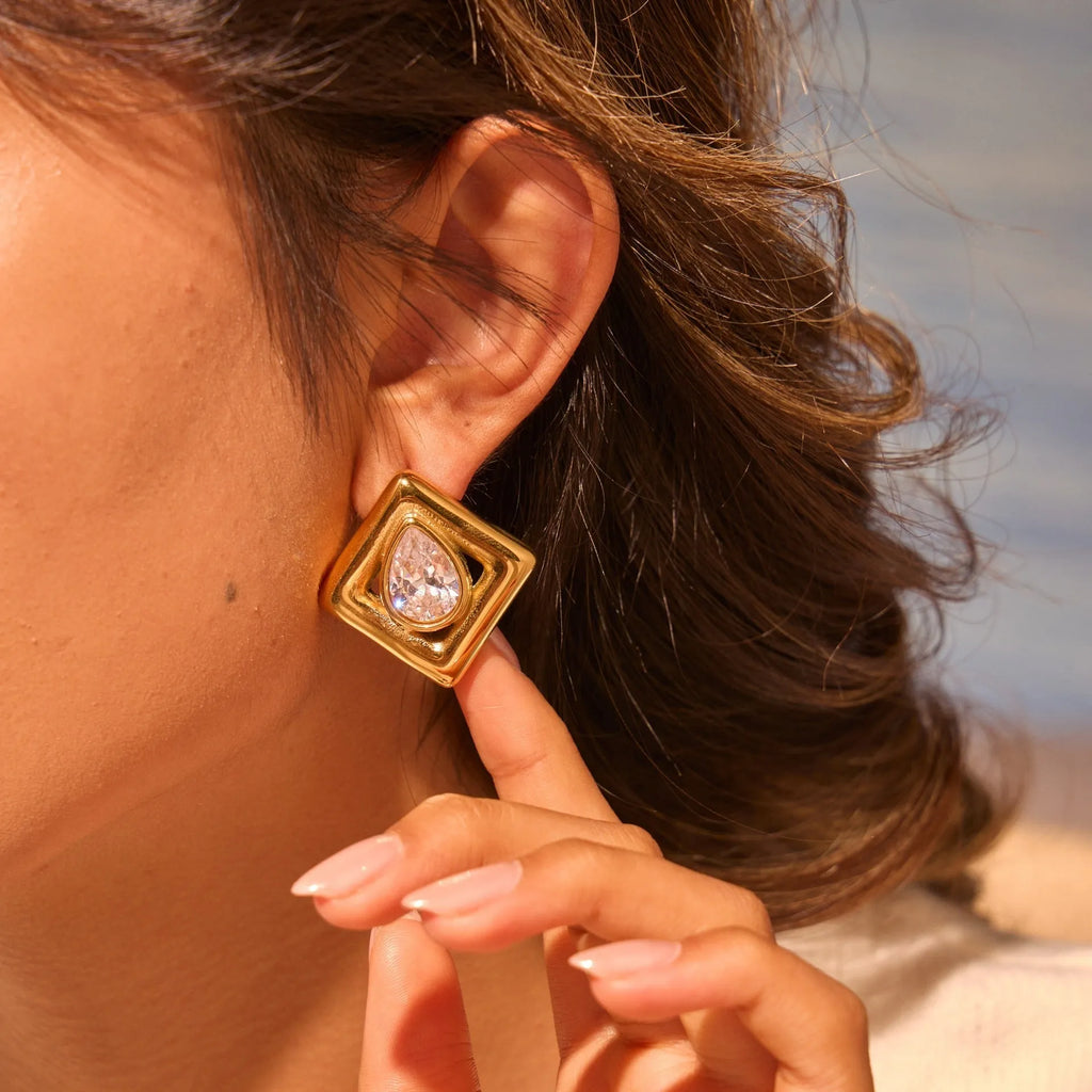 Gold geometric water drop shaped stud earrings with a central zircon stone inlay.