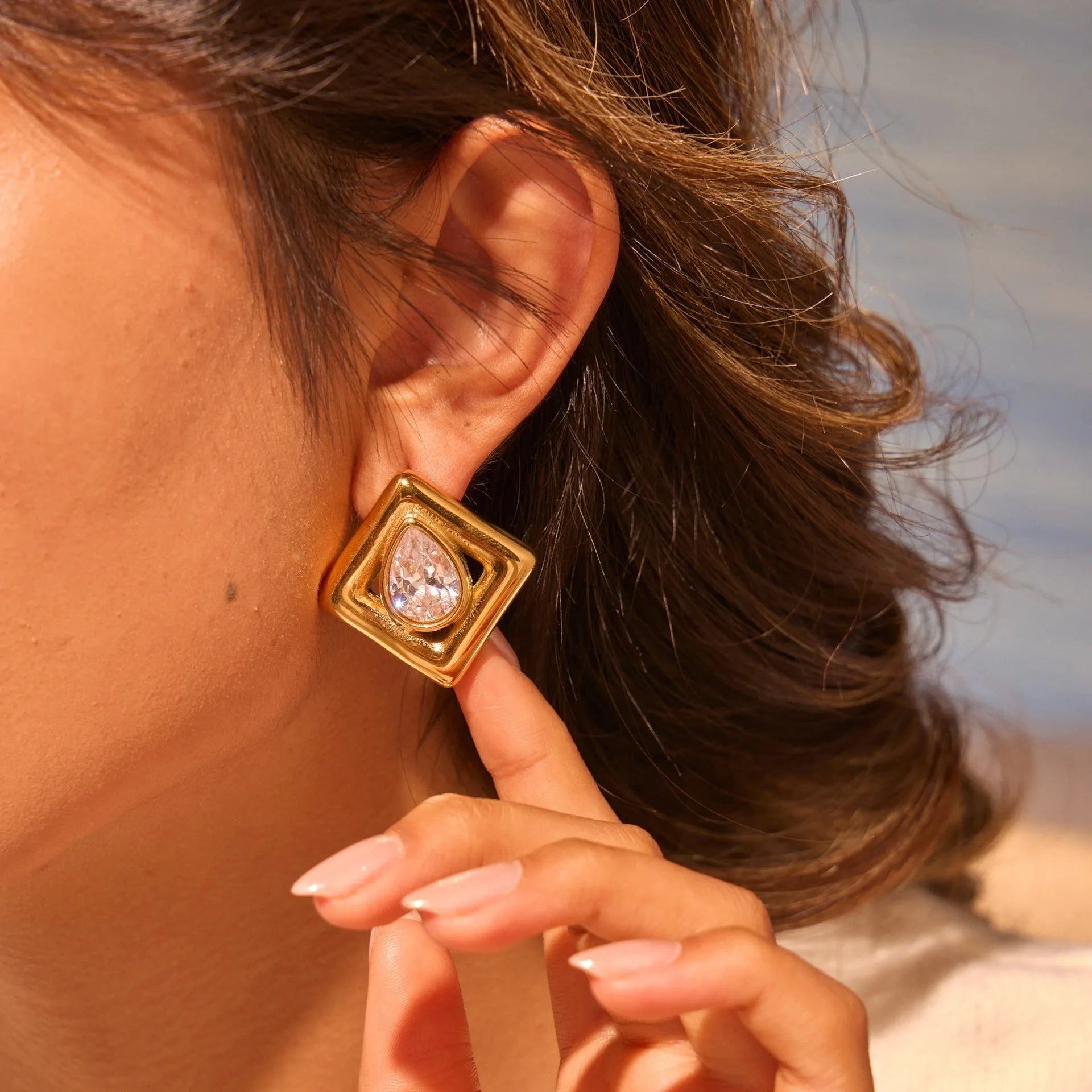 Gold geometric water drop shaped stud earrings with a central zircon stone inlay.