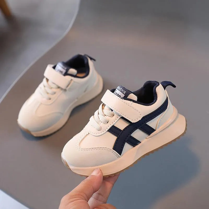 Children's solid-colour sneakers with Velcro strap in white, beige, or khaki on a rubber sole.