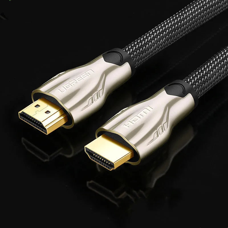 Close-up of a gold-plated HDMI connector on a black cable showing its aluminium foil and braided shielding layers.