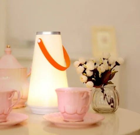 White rechargeable LED bedside lamp with adjustable brightness on a table.