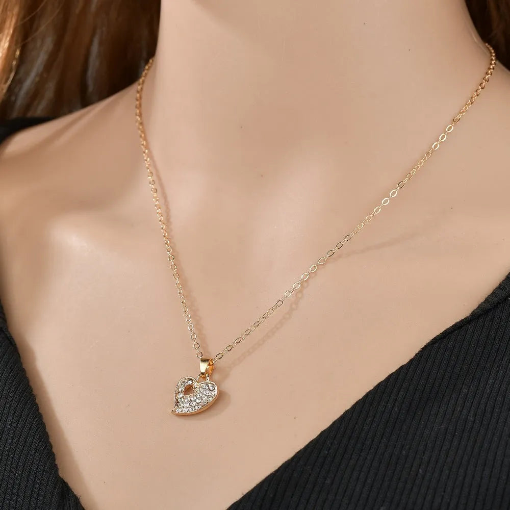 Gold women's jewellery set featuring earrings, an adjustable necklace, and a bracelet with heart, water drop, and bell pendants.