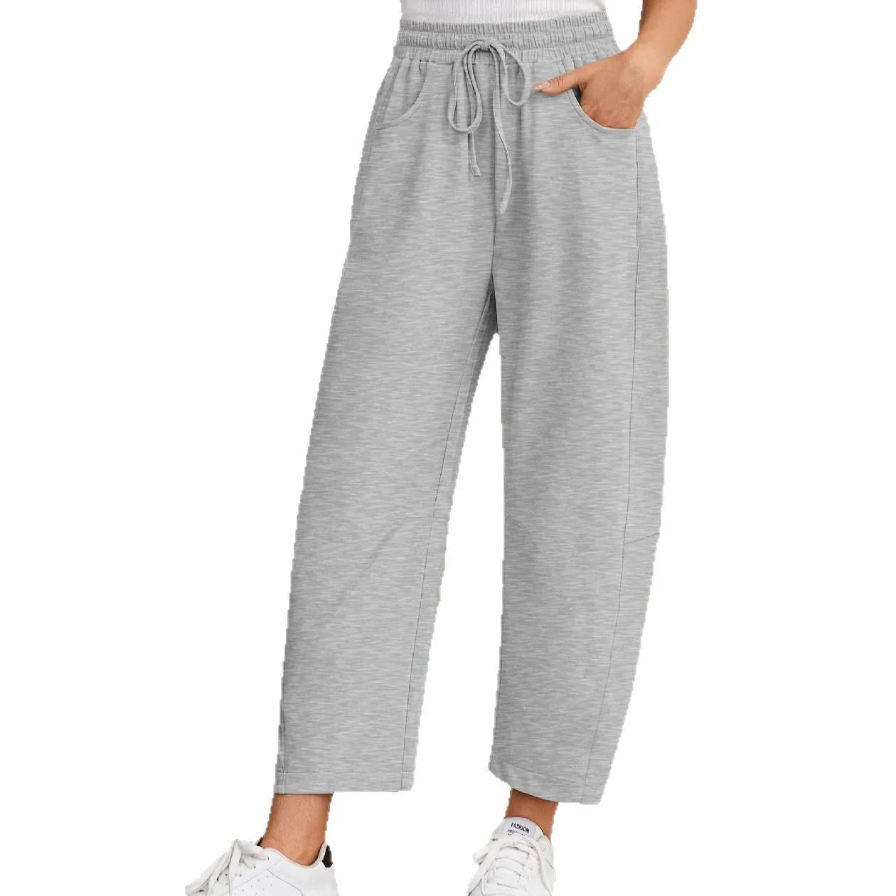 Woman wearing loose grey cropped sweatpants with drawstring waist and side pockets, street fashion style.