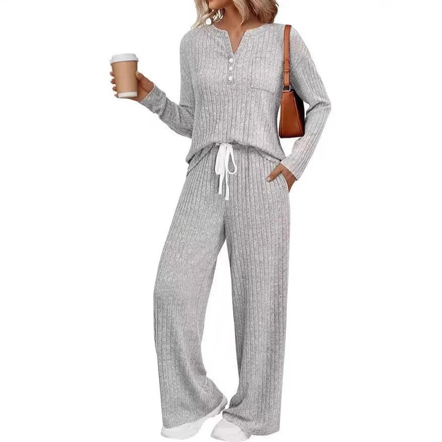 Woman wearing a striped knitted V-neck long coat with matching pants in a light grey colour.