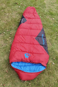 Mummy style camping sleeping bag in a colour option, shown next to its compression sack.