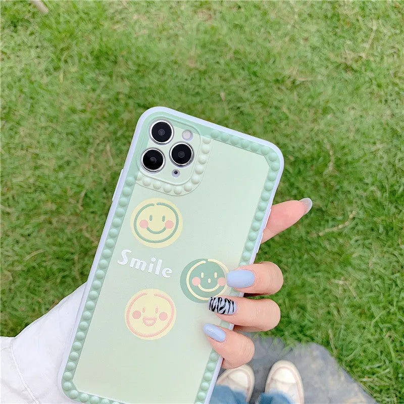 Green geometric pattern iPhone case with smiley faces and polka dot frames on a phone