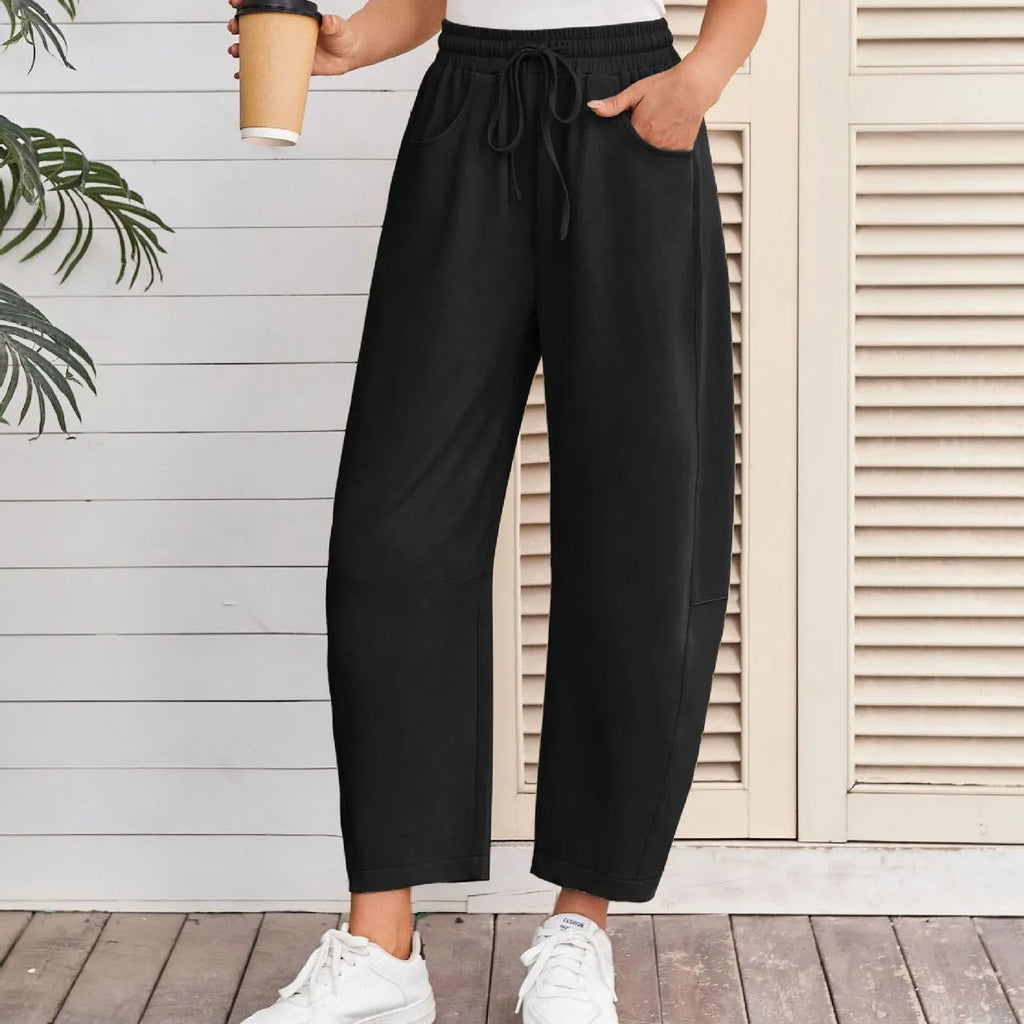 Woman wearing loose grey cropped sweatpants with drawstring waist and side pockets, street fashion style.