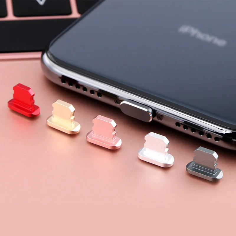 Aluminium alloy iPhone charging port dust plug in metallic colours on a dark background.