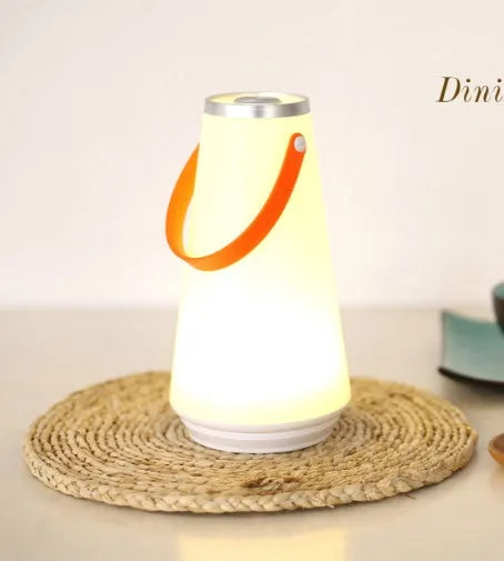 White rechargeable LED bedside lamp with adjustable brightness on a table.